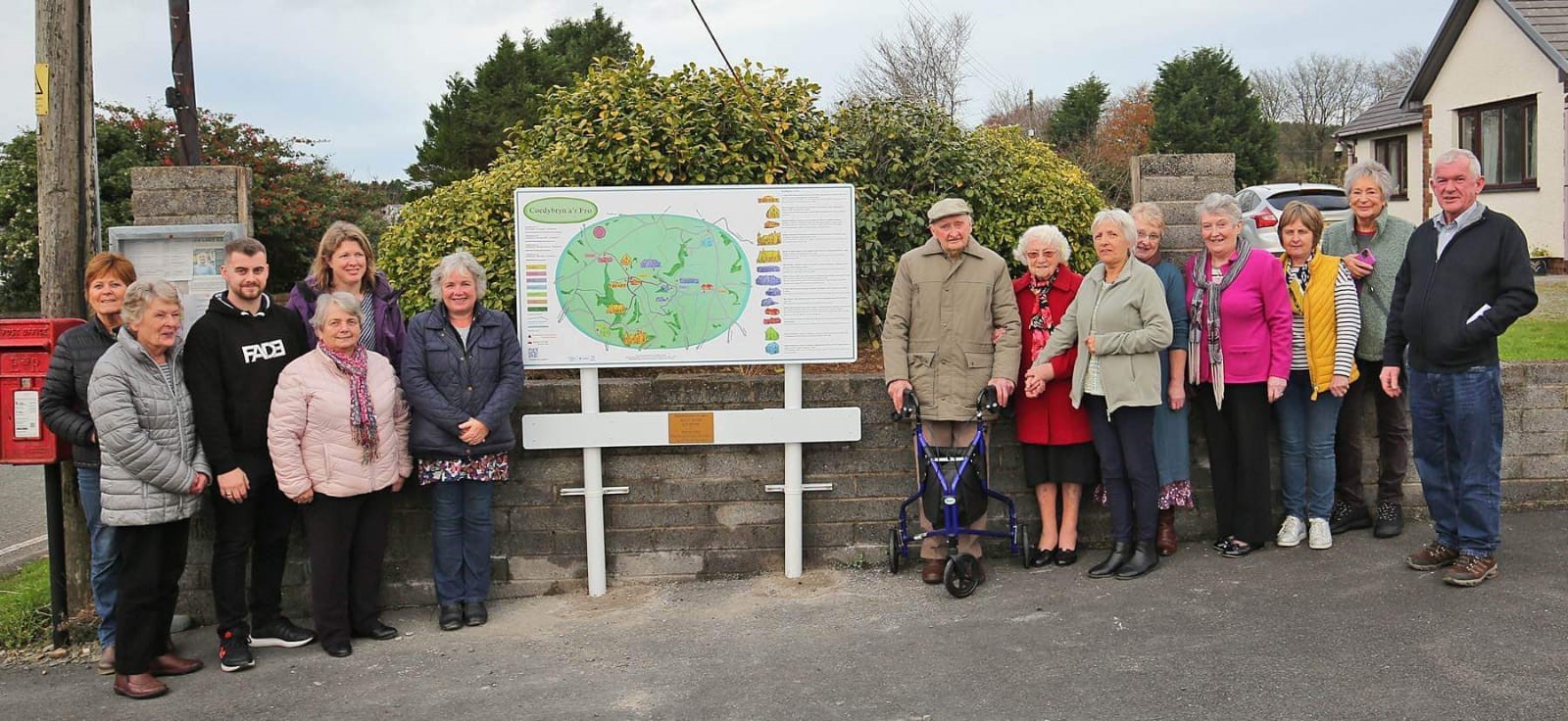 Credit:Llun: Mr Lyn Davies a Mrs Doreen Rees yn sefyll wrth y map darluniadol.  Hefyd yn y llun ma'r cyflwynydd Beti George; dylunydd y gwaith celf, Martha Brown, ac aelodau pwyllgor Cymdeithas Plant Y Bryn, Coedybryn.